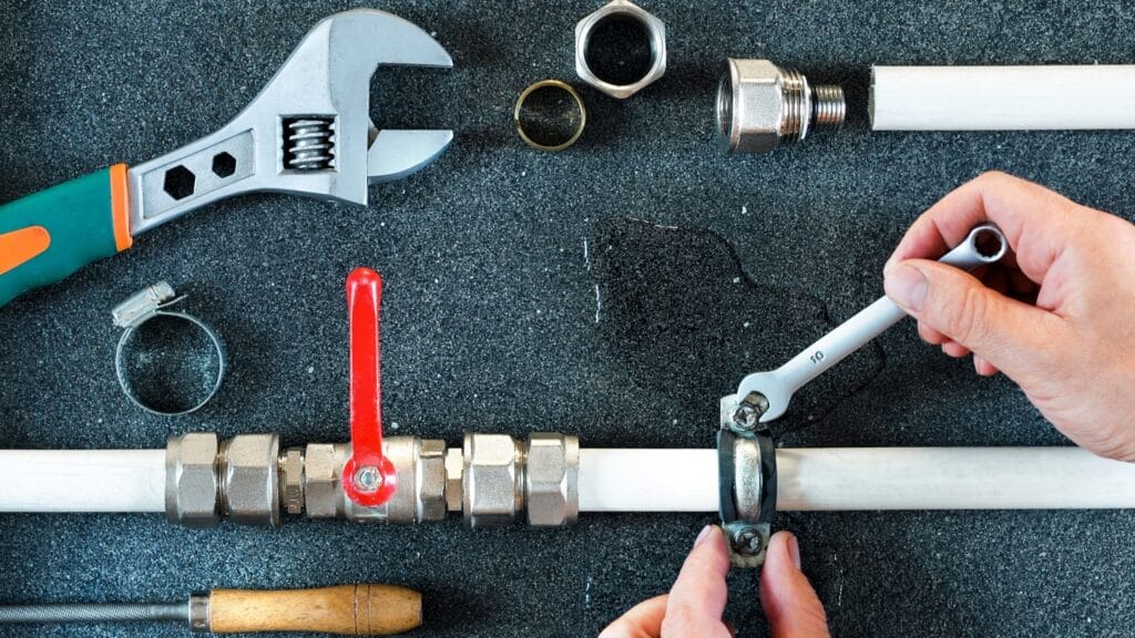 Plumber repairing a pipe valve with an adjustable wrench in Wheat Ridge