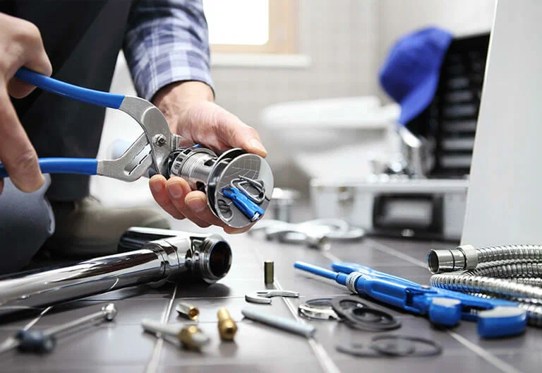 Technician repairing a plumbing fixture with professional tools in Wheat Ridge