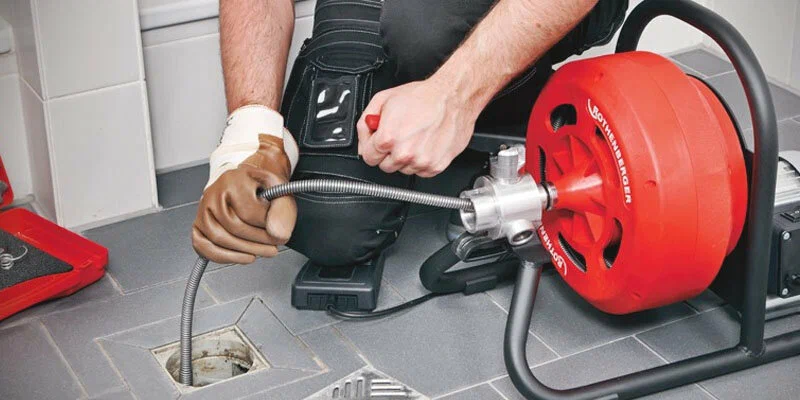 Plumber using a drain-cleaning machine in Wheat Ridge