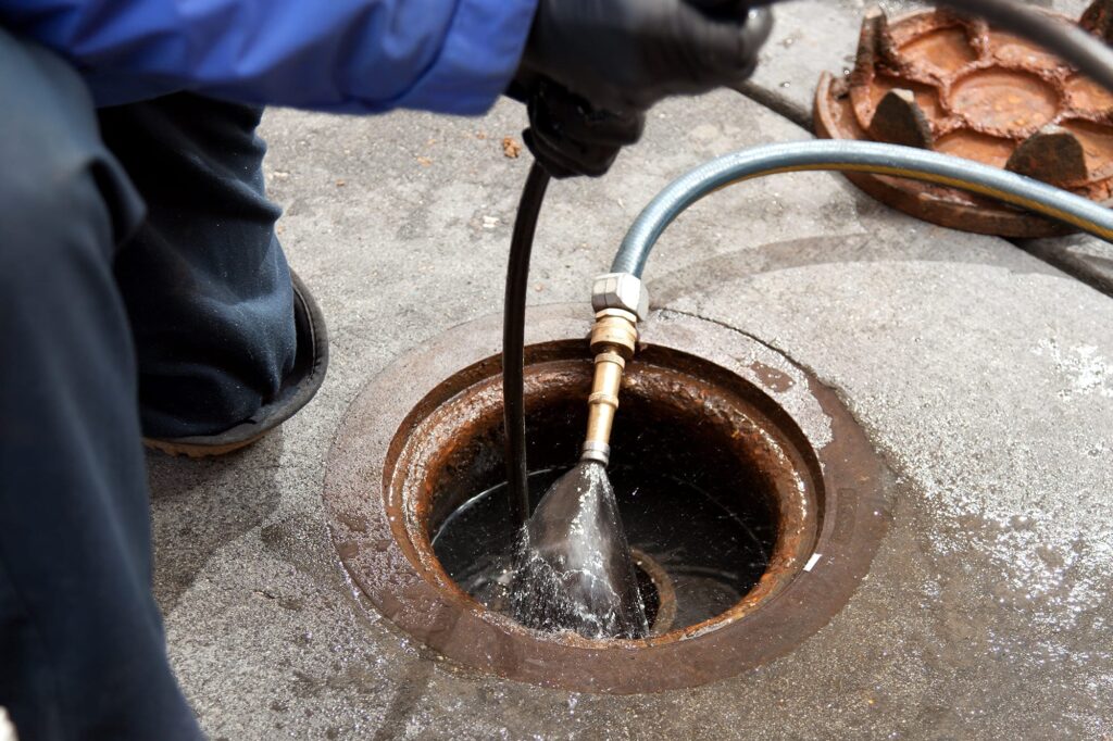 Plumber hydro jetting a sewer line through a manhole in Wheat Ridge