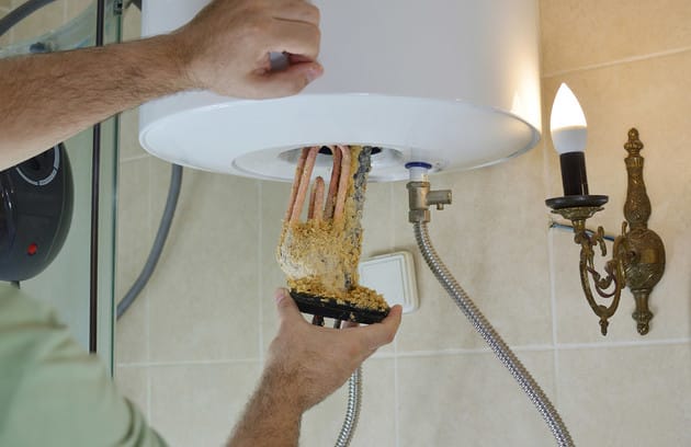 Technician removing mineral buildup from a water heater in Wheat Ridge