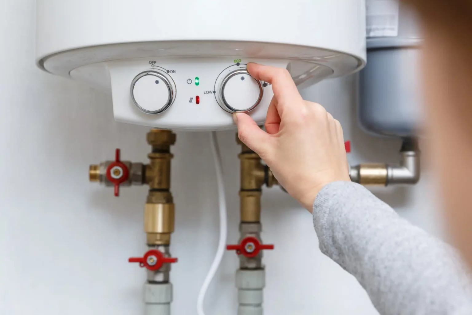 Homeowner adjusting the temperature controls on a water heater in Wheat Ridge